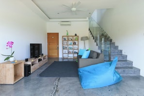 Uma sala de estar moderna com um sofá, uma televisão, uma estante e uma escada.