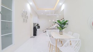 Eine moderne Küche mit weißen Schränken, einem schwarzen Kühlschrank und einem Essbereich mit weißem Tisch und Stühlen.