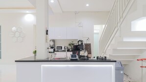 Eine moderne Küche mit weißen Schränken, einer Mikrowelle, einem Wasserkocher und einer Kaffeemaschine.