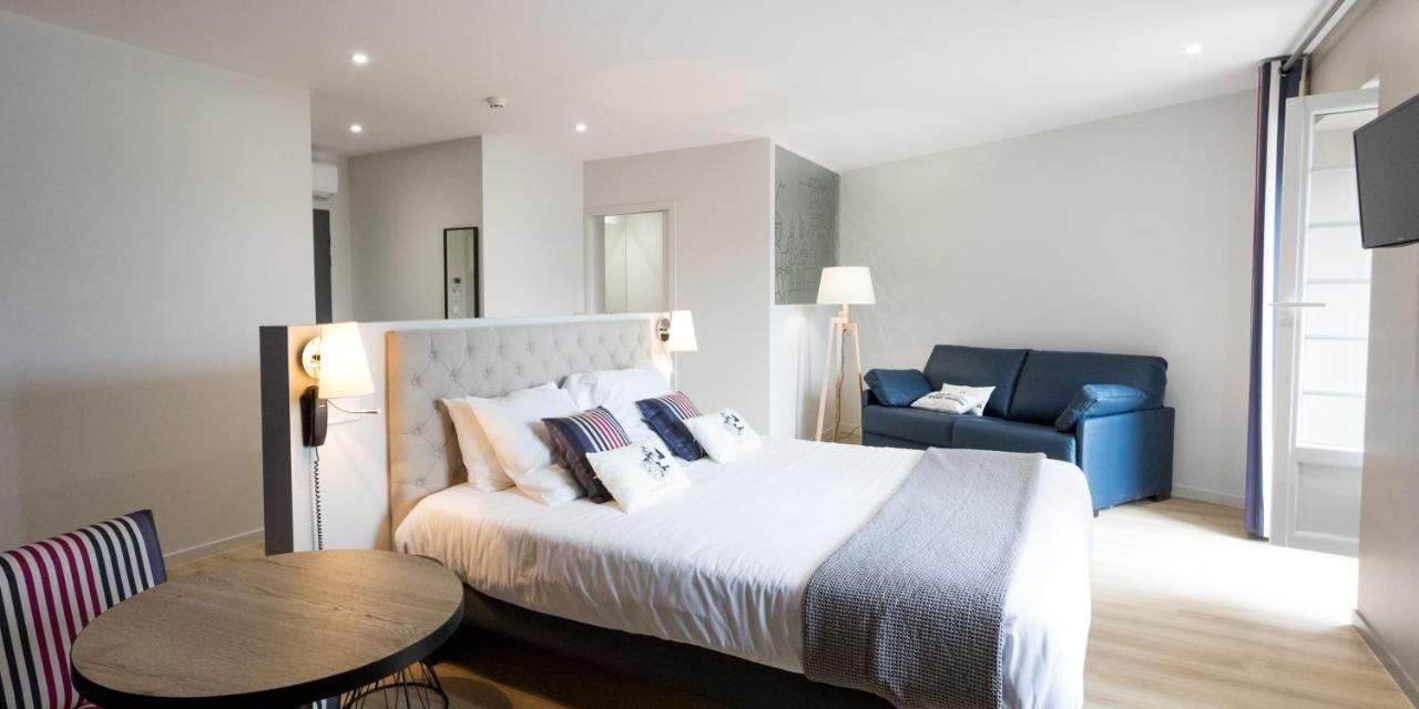 Una habitación de hotel moderna con una cama, un sofá, una mesa redonda y un televisor.