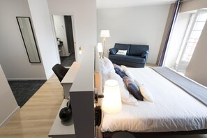 A hotel room with a bed, a desk, a chair, a sofa, a lamp, and a mirror. - Logis Hotel Du Fronton-agian (Itxassou)