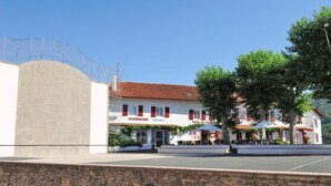 A building with a restaurant, a hotel, and outdoor seating. - Logis Hotel Du Fronton-agian (Itxassou)