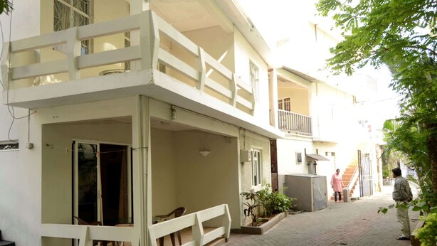 Ein Gebäude mit Balkon, einer Bank und einer Treppe, die zu einer oberen Ebene führt.