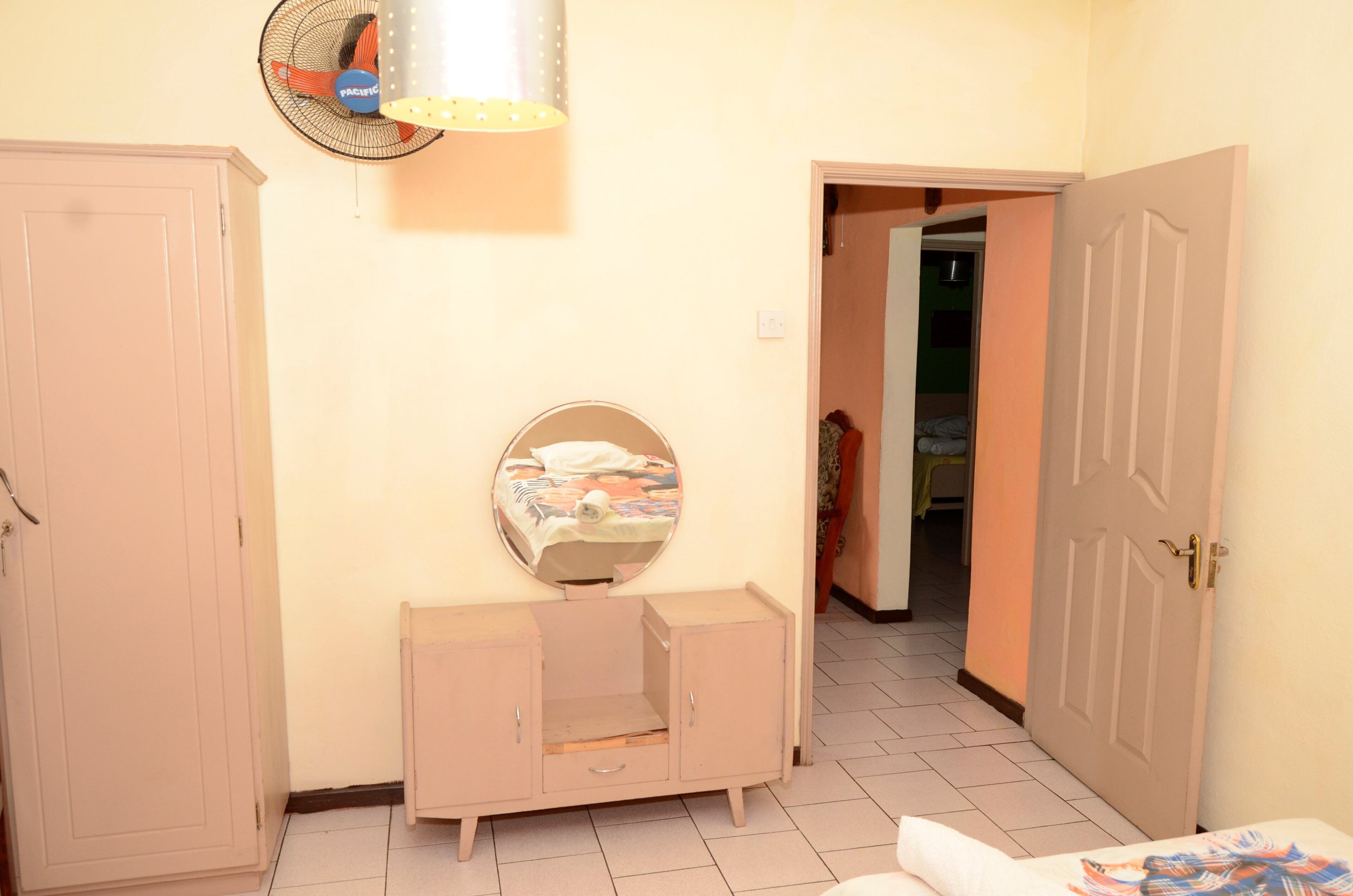 A room with a bed, a wardrobe, a mirror, and a fan.