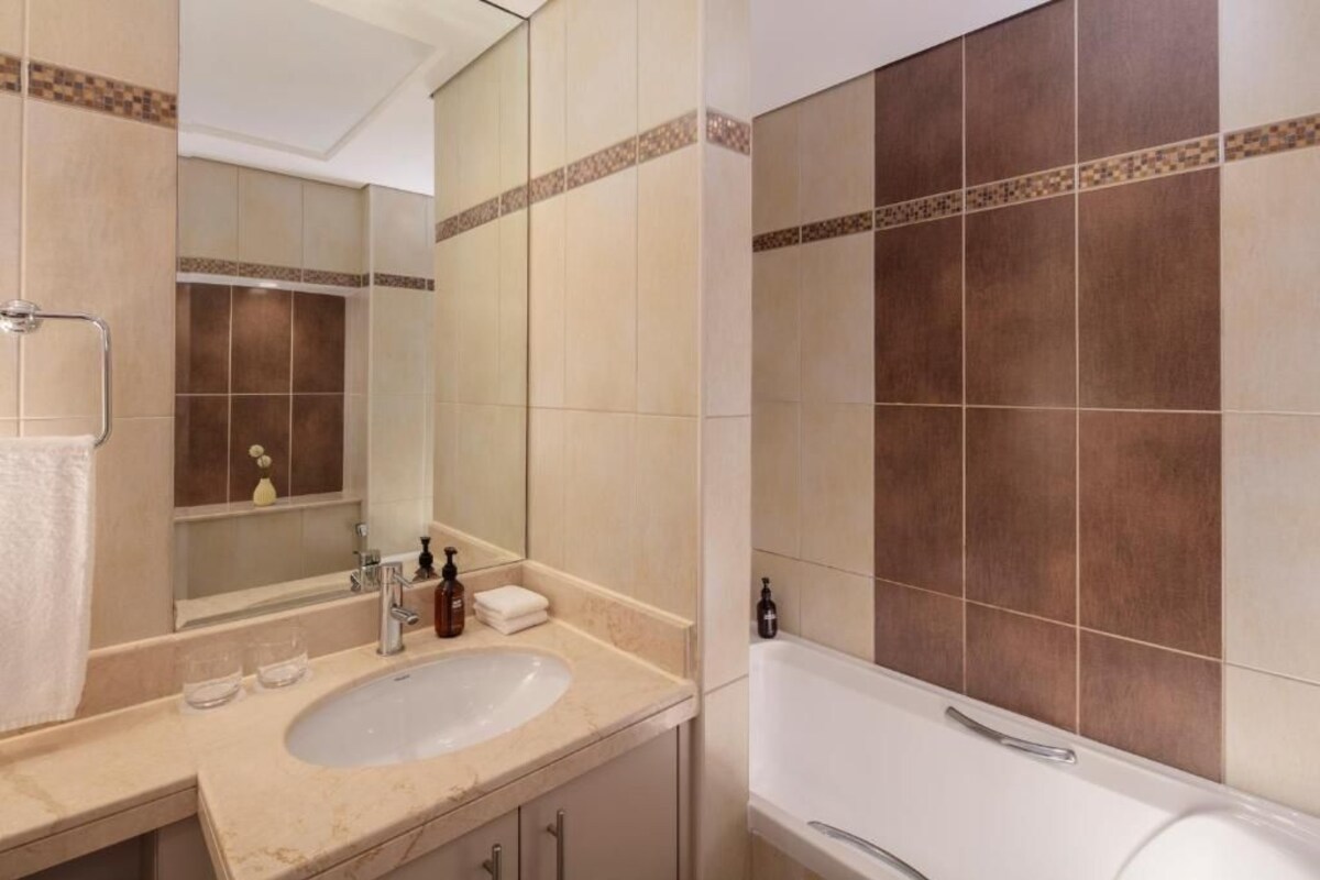 A bathroom with a sink, mirror, and bathtub.