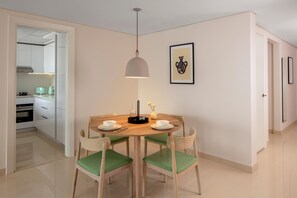 A dining area with a round table, four chairs, a pendant light, and a framed picture on the wall. - Staybridge Suites Dubai Internet City (DUBAI)