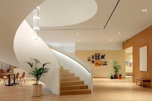 Un interior moderno con una escalera curva, suelo de madera y plantas en macetas.