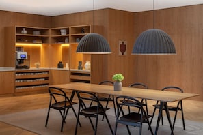 A modern dining area with a wooden table, black chairs, and pendant lights. - Staybridge Suites Dubai Internet City (DUBAI)