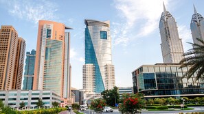 A cityscape with modern high-rise buildings, including a distinctive curved skyscraper and a tall building with a pointed top.