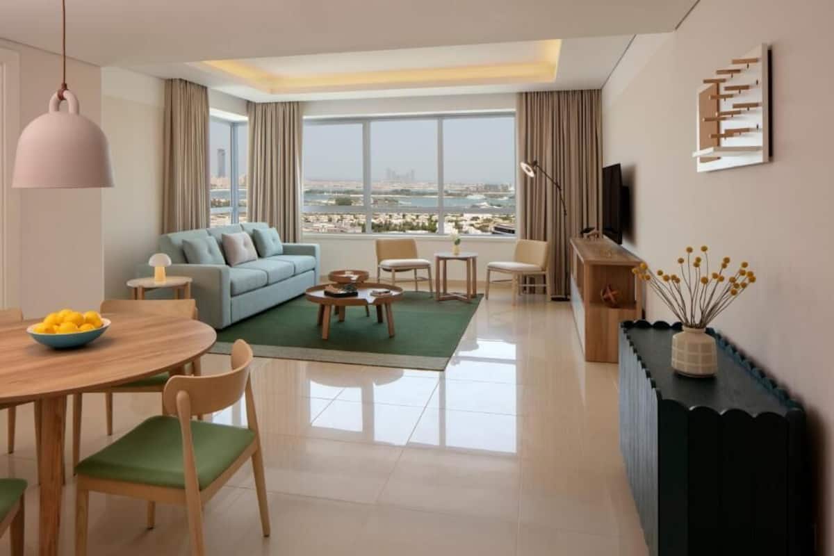 Ein modernes Wohnzimmer mit einer Couch, einem Esstisch, Stühlen, einem Couchtisch, einem Fernseher und Blick auf die Stadt.