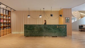A reception desk with a marble top, a wooden bookshelf with various items, and a modern light fixture.