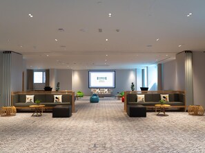 A modern hotel lobby with two sofas, a large screen, and a herringbone-patterned carpet. - Staybridge Suites Dubai Internet City (DUBAI)