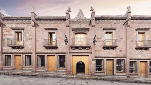 A historic building with multiple balconies, a central archway, and stone walls. - Lotel at Doce18 Concept House (San Miguel de Allende)