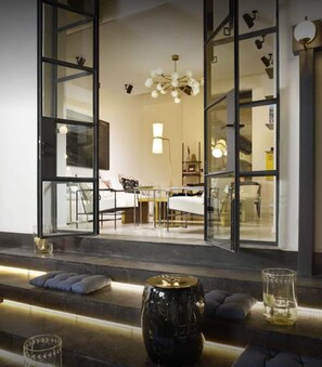 Un intérieur moderne avec un canapé, une table basse et un coin repas visible à travers des portes vitrées.