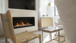 A room with a fireplace, a sofa, a small table, and a chair. - Lotel at Doce18 Concept House (San Miguel de Allende)