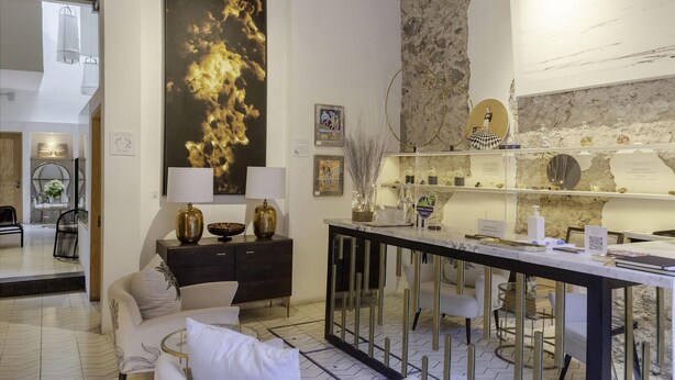 A modern hotel lobby with a large abstract painting, a reception desk, and a seating area. - Lotel at Doce18 Concept House (San Miguel de Allende)