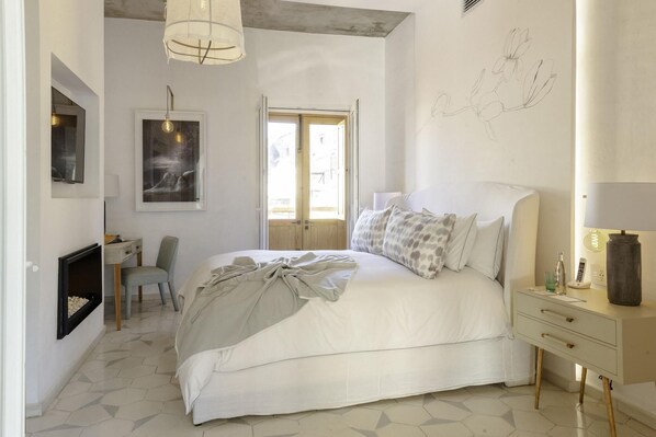 Une chambre à coucher comprenant un lit, une table de chevet, une lampe, une chaise, un bureau et une œuvre d’art.