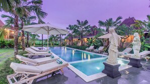 A pool area with lounge chairs, umbrellas, and statues. - Aswanaya Villas & Suite (Ubud)