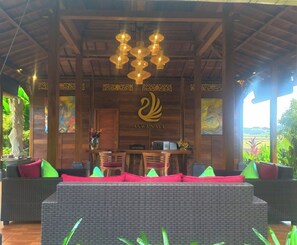 A reception area with a wooden ceiling, a swan logo, a reception desk, and wicker furniture.