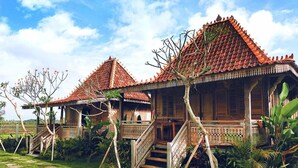 A traditional wooden house with a tiled roof, a staircase, and a well-maintained garden. - Aswanaya Villas & Suite (Ubud)