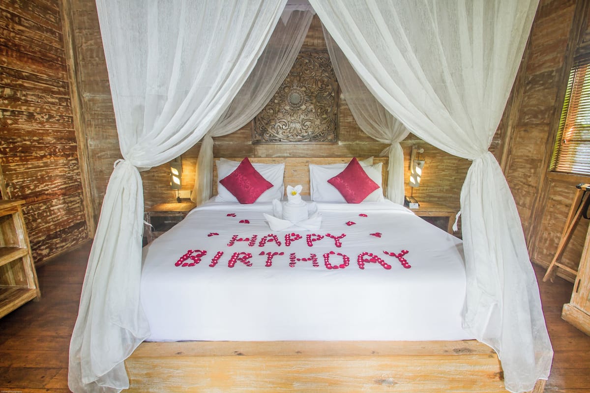Una cama con dosel, cabecera de madera y una decoración de 'Feliz Cumpleaños'.
