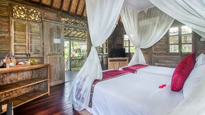 A wooden room with a bed, a TV, and a table with items on it. - Aswanaya Villas & Suite (Ubud)
