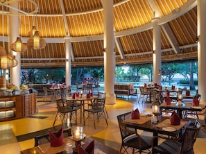 A restaurant with round tables, wicker chairs, and a thatched roof. - Sudamala Resort, Komodo, Labuan Bajo (LABUAN BAJO)