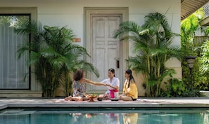 A poolside area with a tiled deck, a door, and lush greenery. - Sudamala Resort, Komodo, Labuan Bajo (LABUAN BAJO)