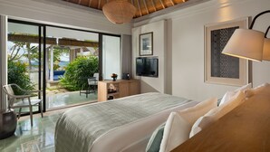 A bedroom with a large bed, a desk, a TV, and a view of the outdoors.