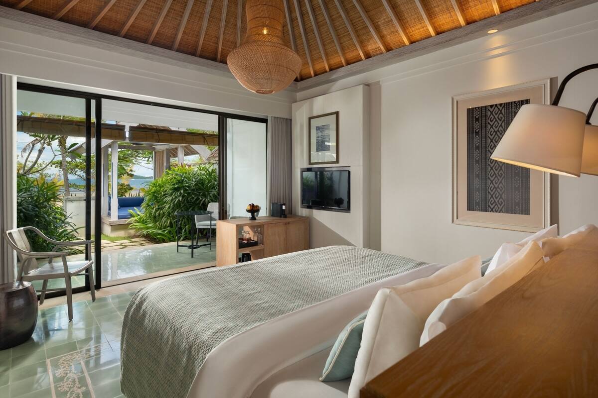 Un dormitorio con una cama grande, un escritorio, un televisor y vistas al exterior.