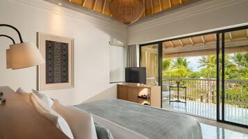 Un dormitorio con cama, televisor, escritorio y un ventanal con vistas a palmeras.