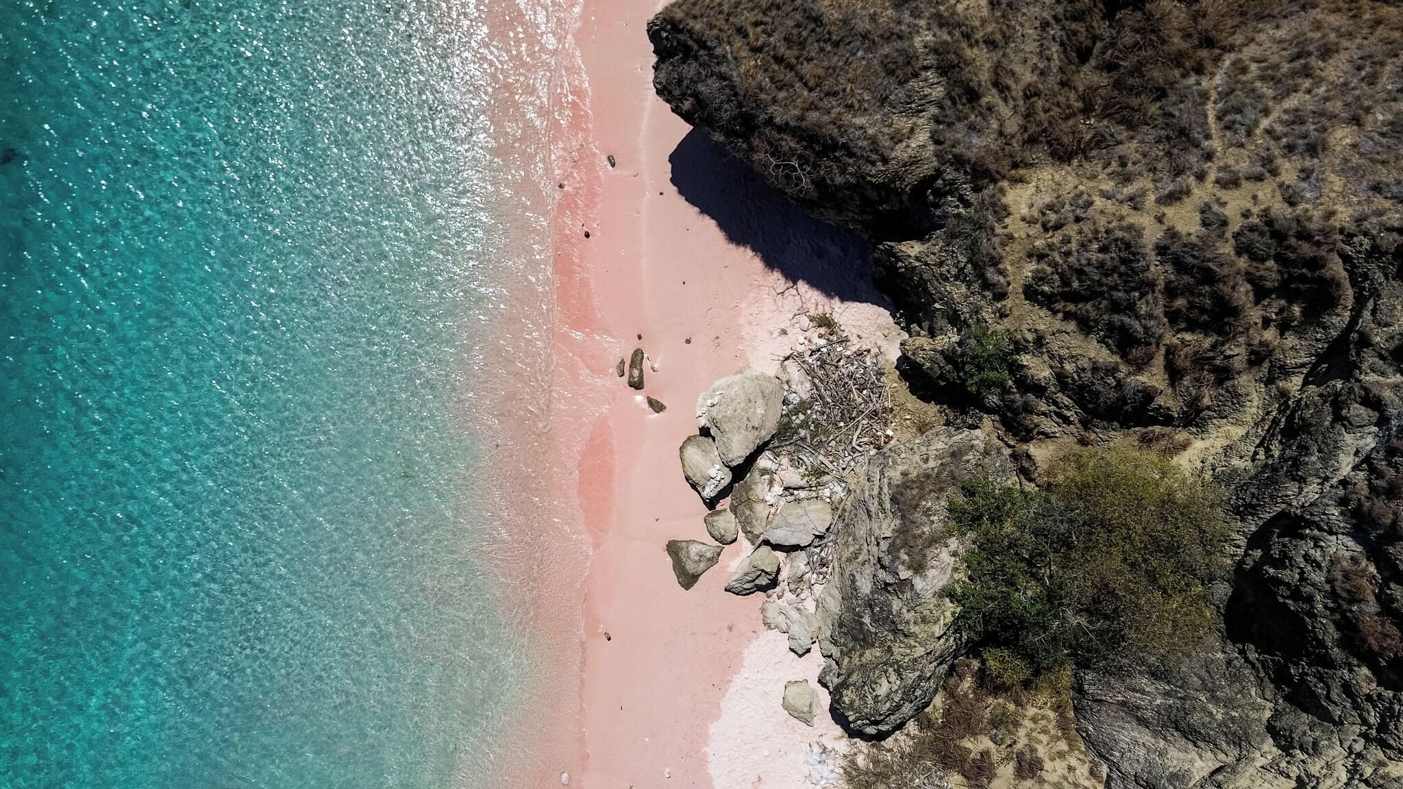 Un paisaje costero con una playa despejada, acantilados rocosos y un mar tranquilo.