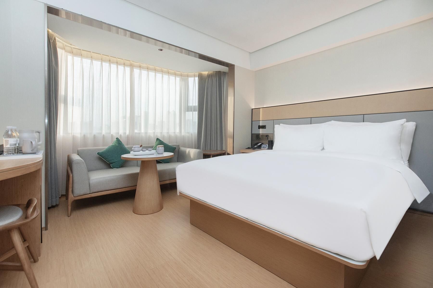 Quarto de hotel com cama, sofá, uma mesinha e escrivaninha.
