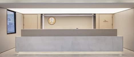 A reception desk with a minimalist design, a wall-mounted sign with Chinese characters, and a door to the right.