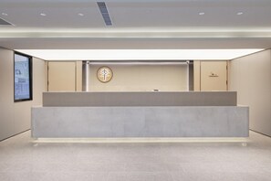 Un comptoir d’accueil au design minimaliste, une enseigne fixée au mur avec des caractères chinois, et une porte sur la droite.
