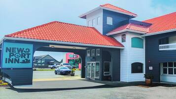 Ein New Port Inn mit rotem Ziegeldach, überdachter Eingangspartei und einem Parkplatz mit Autos.
