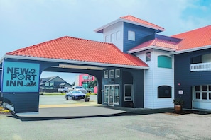 A New Port Inn with a red-tiled roof, a covered entrance, and a parking lot with cars. - Newport Inn By OYO - Hwy 101 (Mapleton)