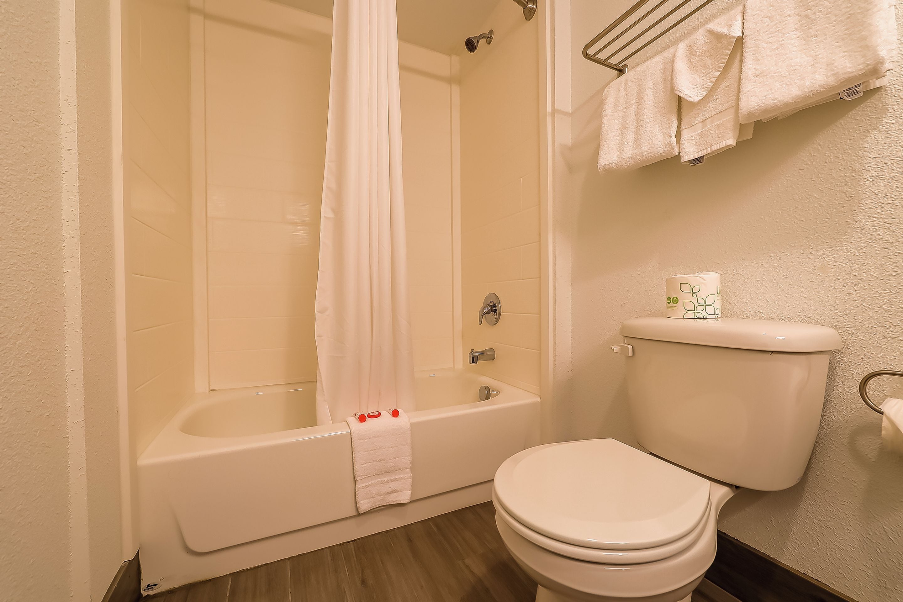 A bathroom with a bathtub, toilet, and shower curtain.