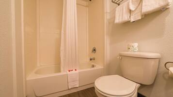 A bathroom with a bathtub, toilet, and shower curtain.