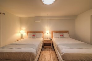 A hotel room with two beds, each with a bedside table and lamp, and a small wooden nightstand between them. - Newport Inn By OYO - Hwy 101 (Mapleton)