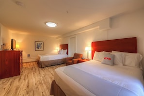 A hotel room with two beds, a desk, and a chair.