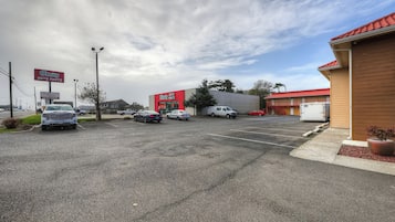 Un estacionamiento al aire libre con varios coches, un edificio con techo rojo y un cartel de 'O'Reilly Auto Parts'.
