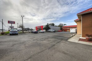 Un estacionamiento al aire libre con varios coches, un edificio con techo rojo y un cartel de 'O'Reilly Auto Parts'.