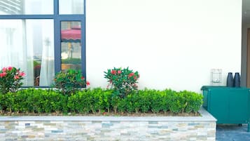 A landscaped garden with hedges and flowering plants, a stone wall, and a green cabinet.