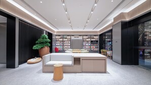 A modern library interior with a central seating area, bookshelves, and a decorative tree. - Ji Hotel (Chengdu)