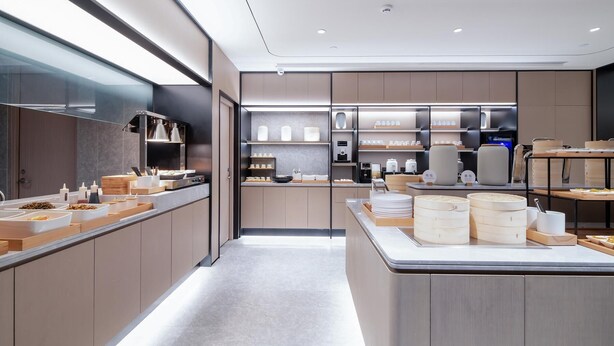 A modern kitchen with a long counter, built-in appliances, and a variety of food items displayed. - Ji Hotel (Chengdu)
