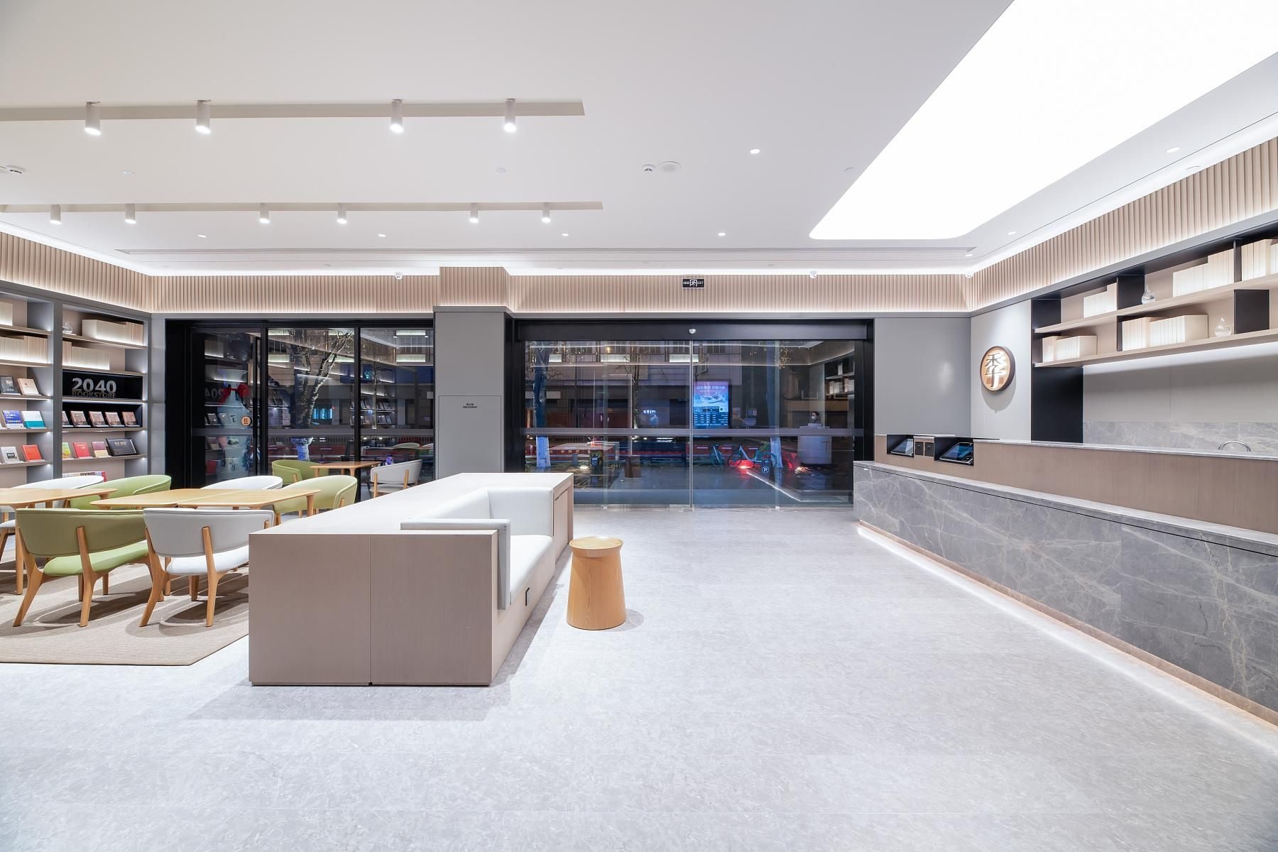 Un moderno vestíbulo de hotel con una recepción, zona de estar y una librería.