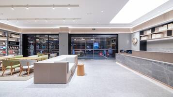 Un moderno vestíbulo de hotel con una recepción, zona de estar y una librería.