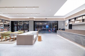 A modern hotel lobby with a reception desk, seating area, and a bookstore. - Ji Hotel (Chengdu)
