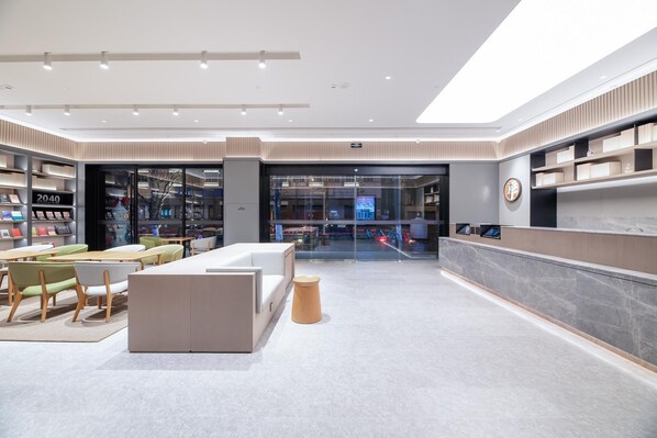 Um hall de hotel moderno com uma mesa de recepção, área de estar e uma livraria.